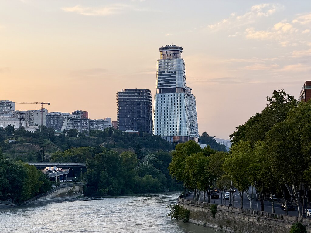 Fluss Kura in Tiflis, dahinter Hochhäuser und daneben eine Straße