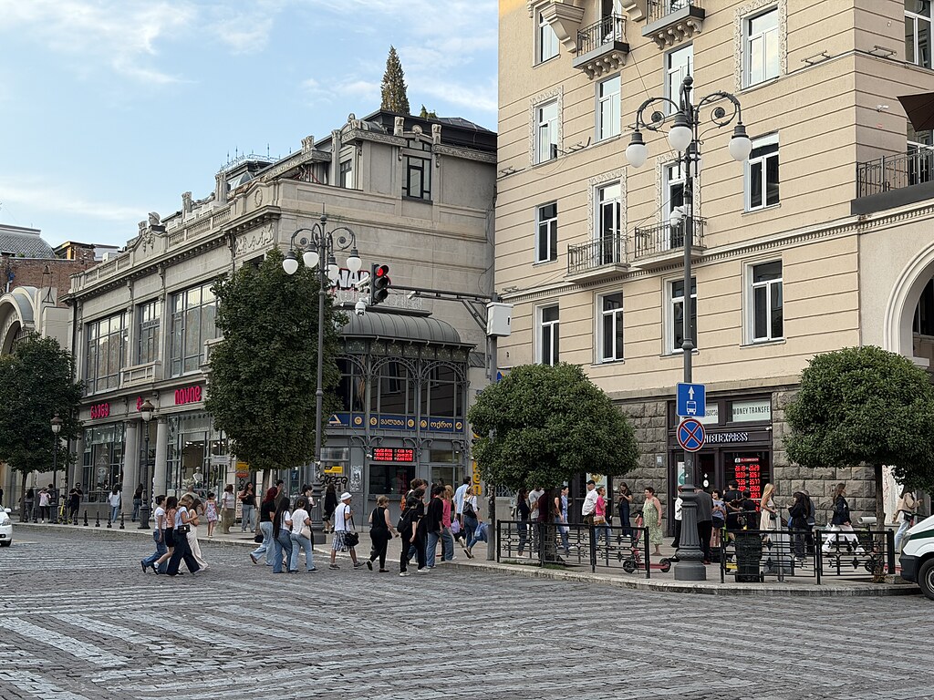 Eine grüne Fußgängerampel an der Kreuzung K. Marjanishvili Square in Tiflis. Fußgänger gehen über die Straße