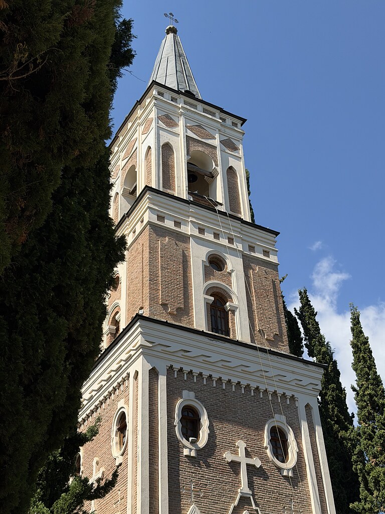 Alter Turm vom Kloster Bodbe umgeben von grünen Bäumen und blauem Himmel.