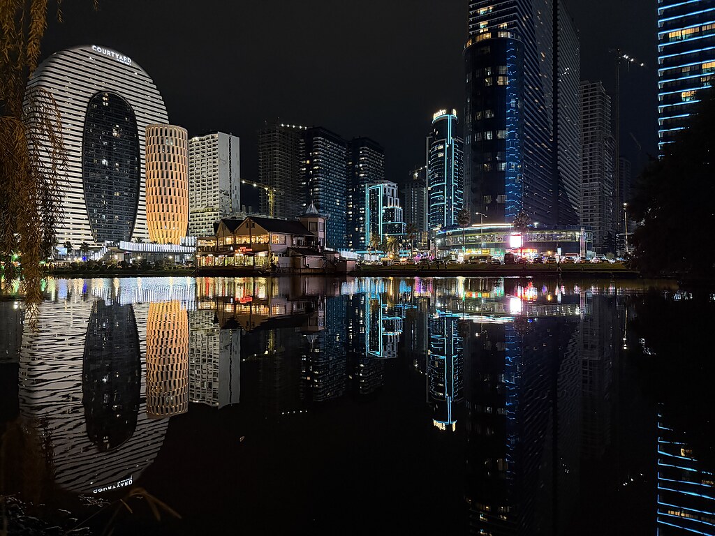 Spiegelndes, bunt beleuchtetes Stadtpanorama von Batumi, Georgien auf dem Wasser.