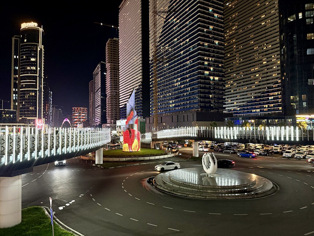 Ice Skating Ring , Kreisverkehr und beleuchtete Brücke mit Hochhäusern in Batumi, Georgien