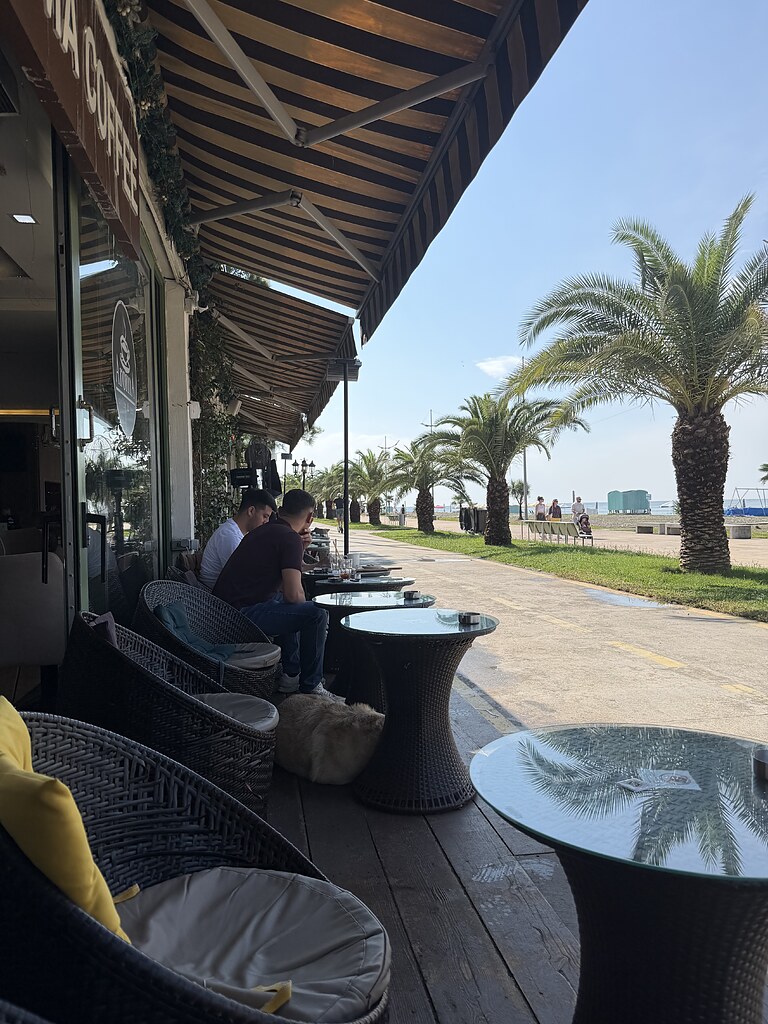 Außenbereich vom Aroma Coffee and Tea Café mit Blick auf das Schwarze Meer und Palmen in Batumi, Georgien.