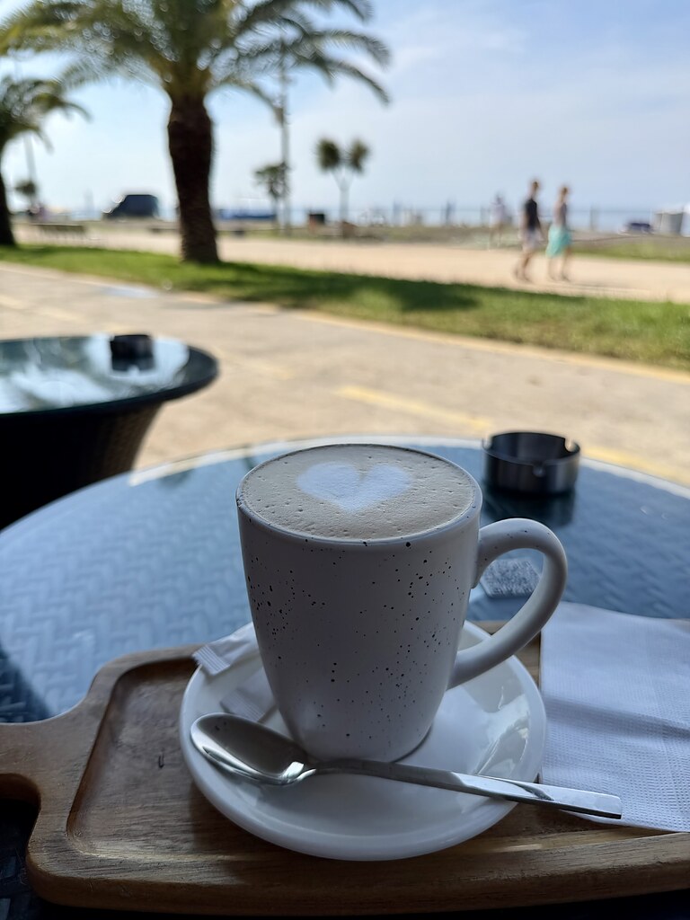 Cappuccino mit Herz im Aroma Coffee and Tea Café mit Blick auf das Schwarze Meer und Palmen in Batumi, Georgien.