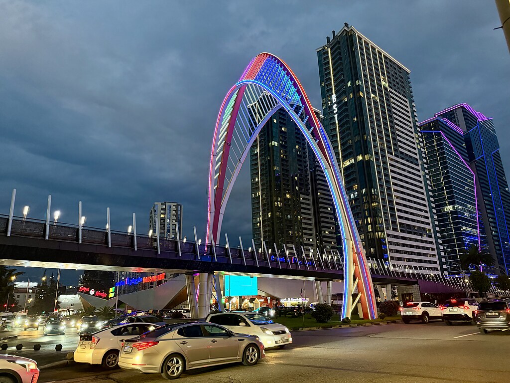 Black Sea Arch, beleuchtete Fußgänger Brücke, darunter eine Straße mit Verkehr in Batumi, Georgien.
